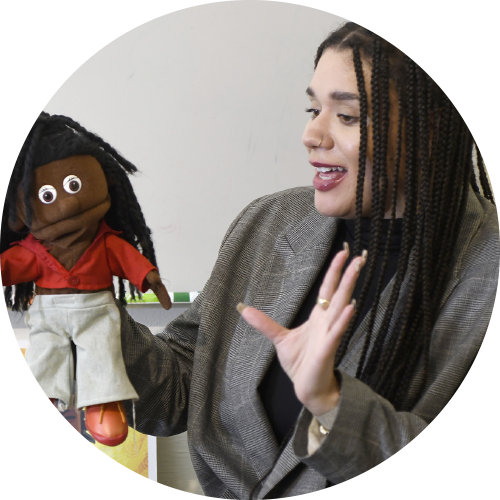 An image of a woman of colour holding a puppet as part of one of the programs for children.